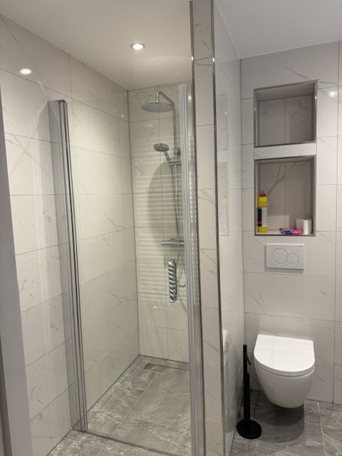 Douche met regendouchekop, wandcloset en nisjes in een nieuwe badkamer