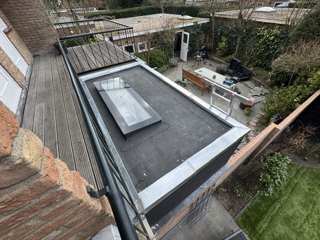 Nieuw plat dak met lichtkoepel en zinken dakrand, van bovenaf gezien