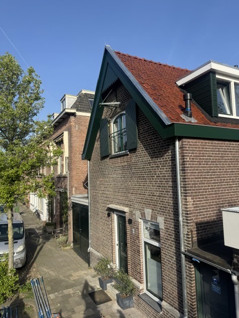Baksteen woning met vernieuwd rood pannendak, groene gevel en nieuwe regenpijp